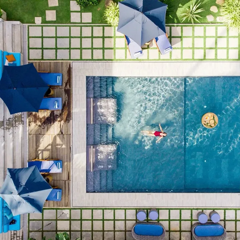 Vue aérienne d'une piscine avec une personne nageant et des transats