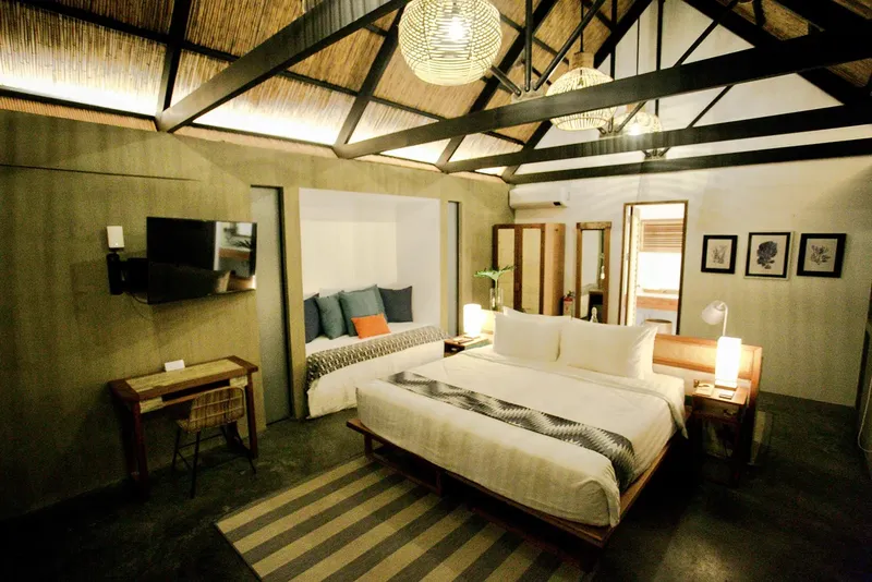 Chambre d'hôtel avec deux lits, bureau, décoration naturelle et éclairage chaleureux