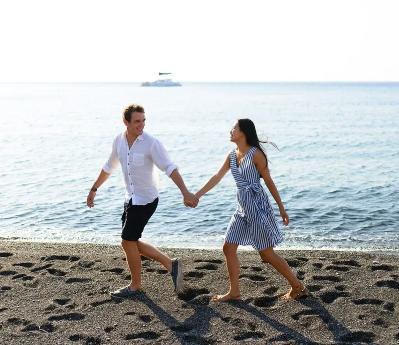 Un couple se promène main dans la main sur une plage sombre