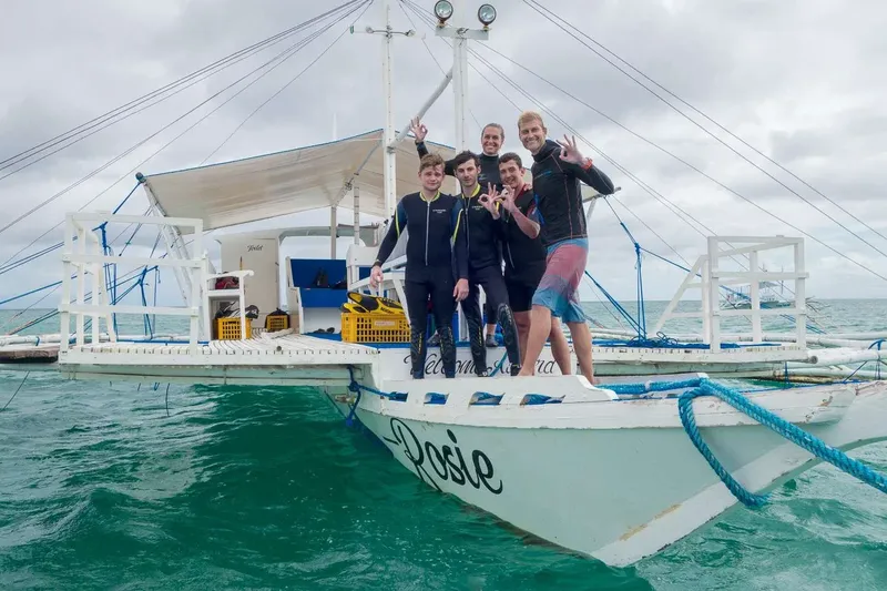 Quatre personnes souriantes sur un bateau de plongée en mer