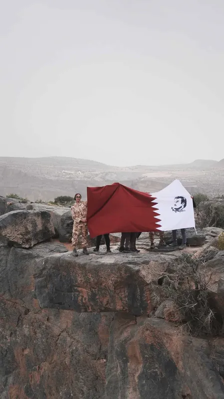 Personnes tenant un drapeau sur un promontoire rocheux en extérieur