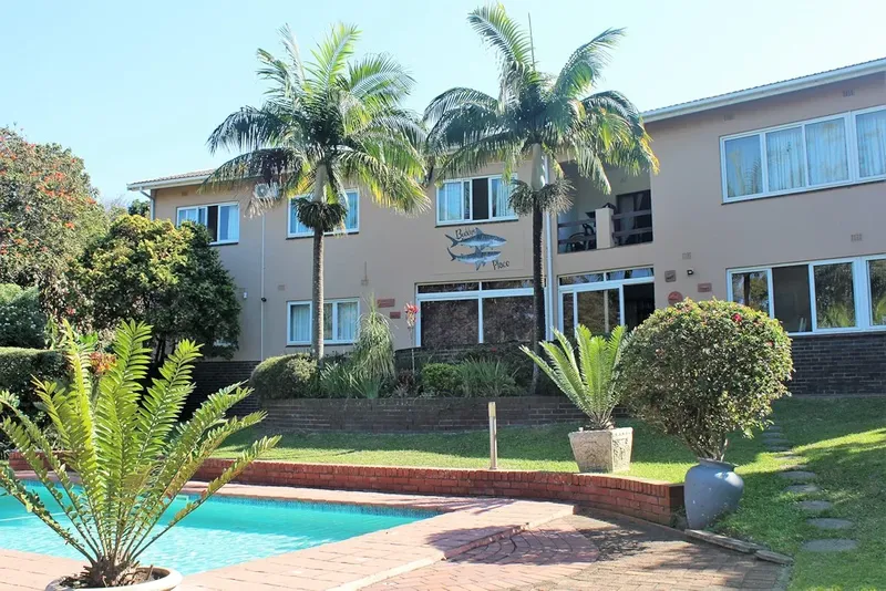 Bâtiment beige avec palmiers et piscine au premier plan