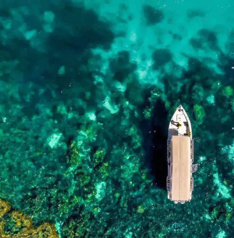 Vue aérienne d'un bateau de plongée au-dessus d'un récif corallien turquoise