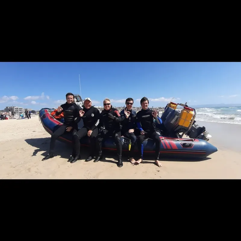 Plongée : groupe de personnes souriantes sur un bateau pneumatique à la plage