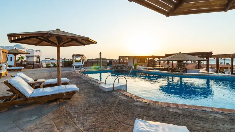 Terrasse avec piscine, transats et parasols au coucher du soleil