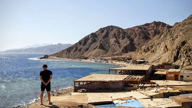 Homme regardant la mer depuis une terrasse avec bâtiments en arrière-plan