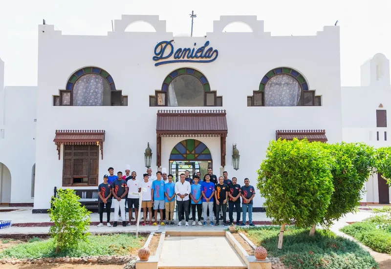 Groupe de personnes posant devant un bâtiment blanc orné d'arches