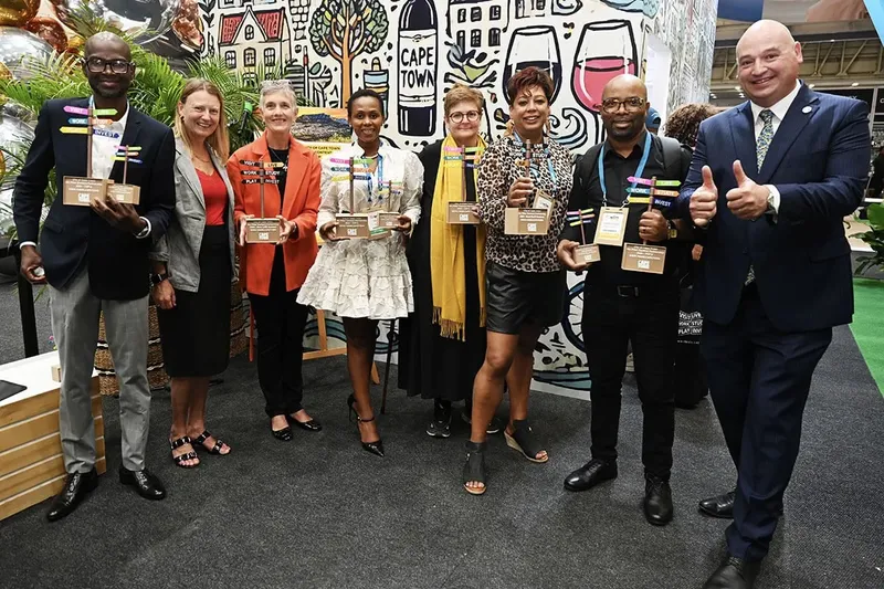 Groupe de personnes souriantes tenant des trophées devant un mur décoré