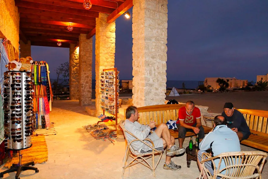 Quatre personnes assises et discutant sur une terrasse éclairée