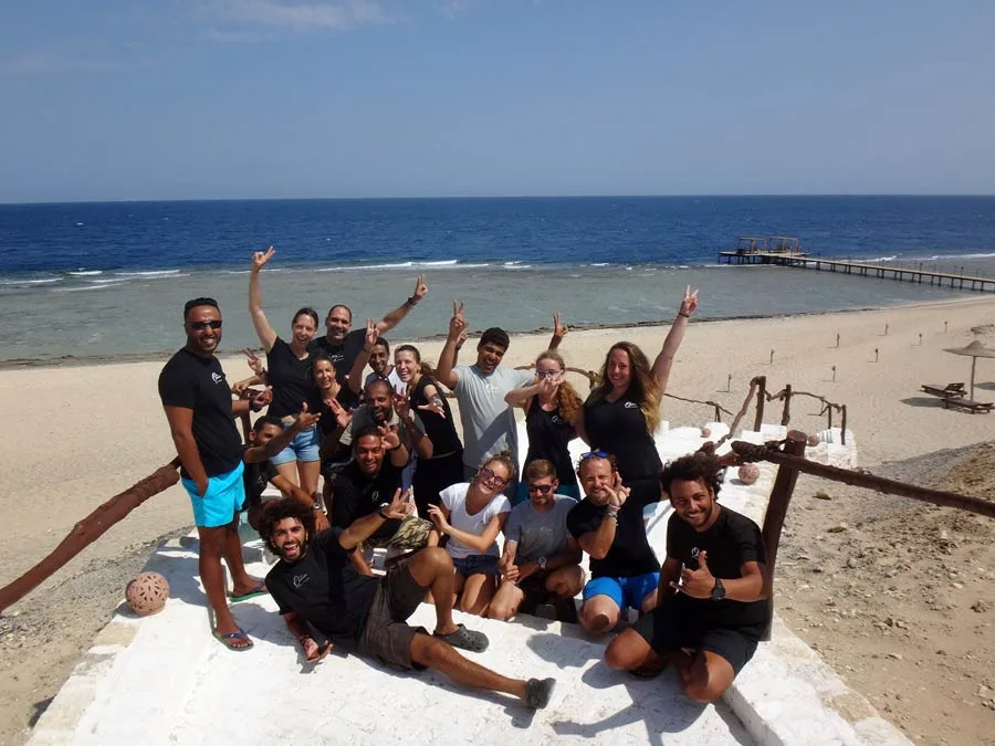 Groupe de personnes souriantes sur une plage ensoleillée avec la mer