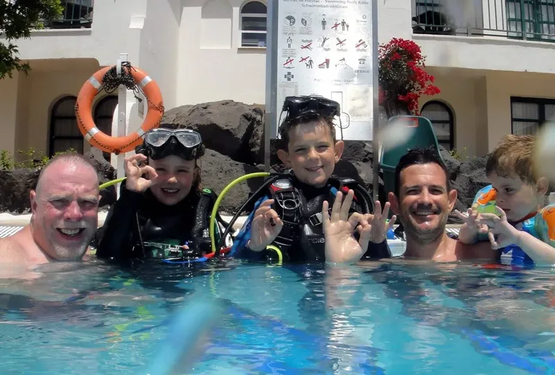 Groupe de personnes souriantes avec du matériel de plongée dans une piscine