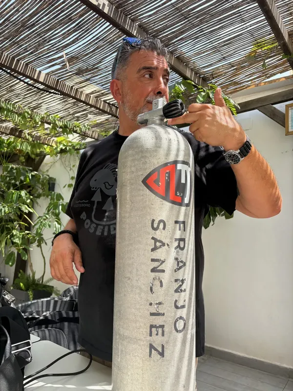 Un homme tient une bouteille de plongée avec son nom inscrit