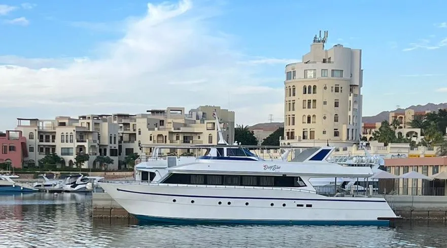 Grand bateau de plongée amarré dans un port ensoleillé avec bâtiments