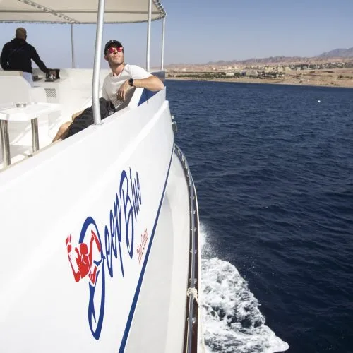 Deux hommes sur un bateau de plongée en mer, paysage côtier
