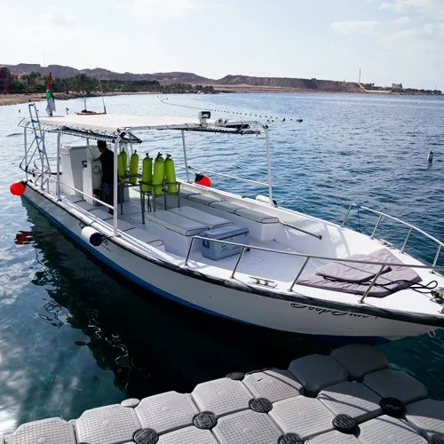 Bateau de plongée blanc amarré à un ponton modulaire en mer