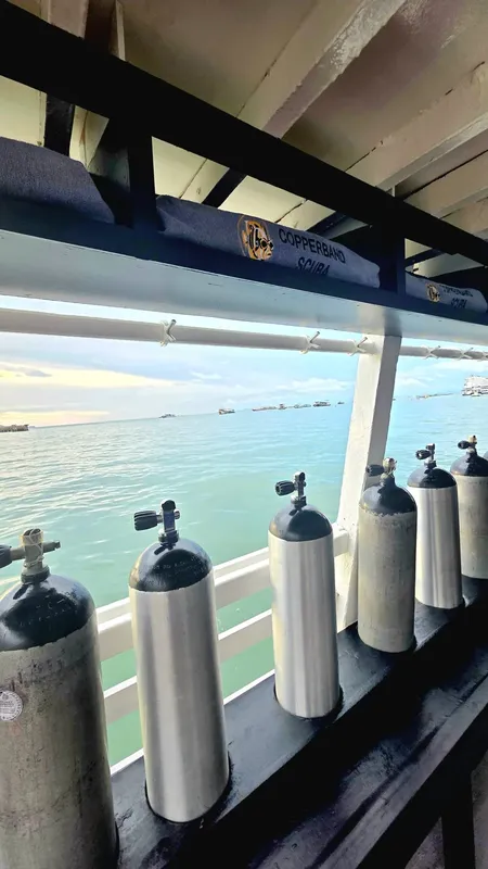 Bouteilles de plongée alignées sur un bateau avec vue sur la mer