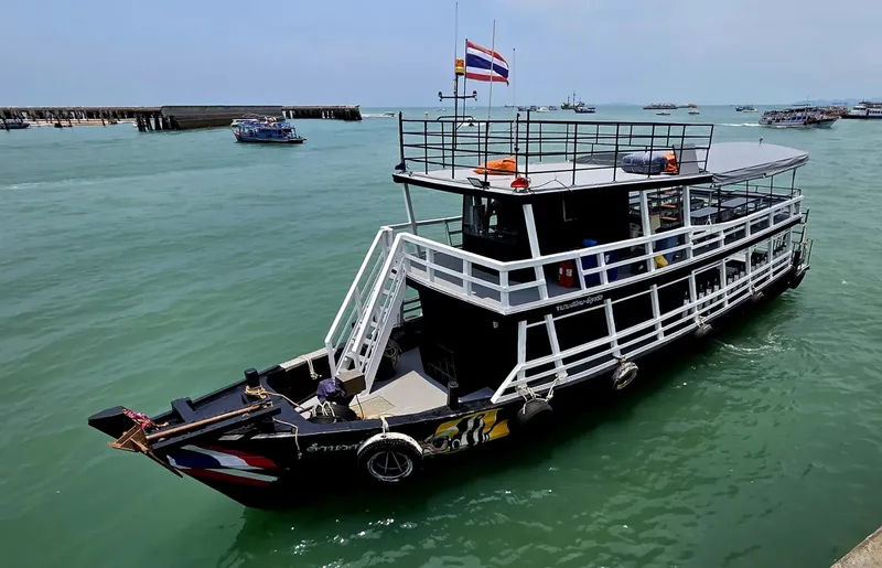Bateau de plongée amarré dans une eau verte, drapeau thaïlandais