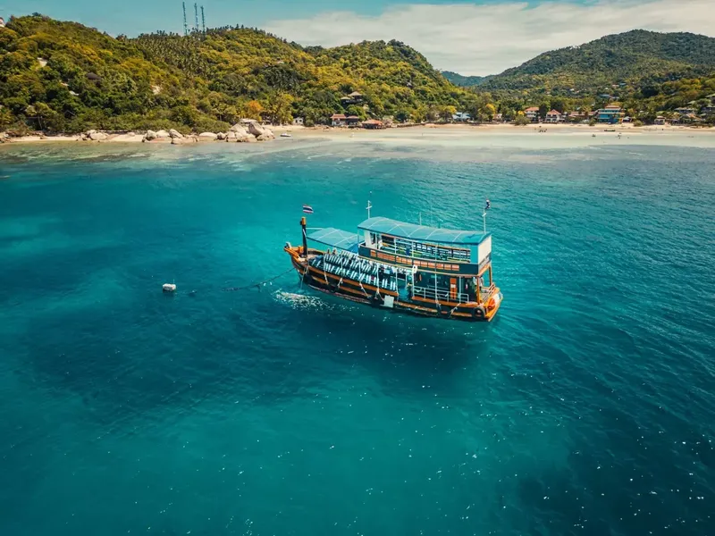 Bateau traditionnel longtail en mer turquoise devant une plage tropicale