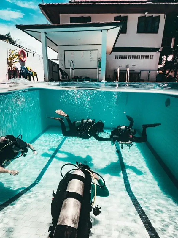 Plongeurs en formation dans une piscine, équipement complet, eau turquoise