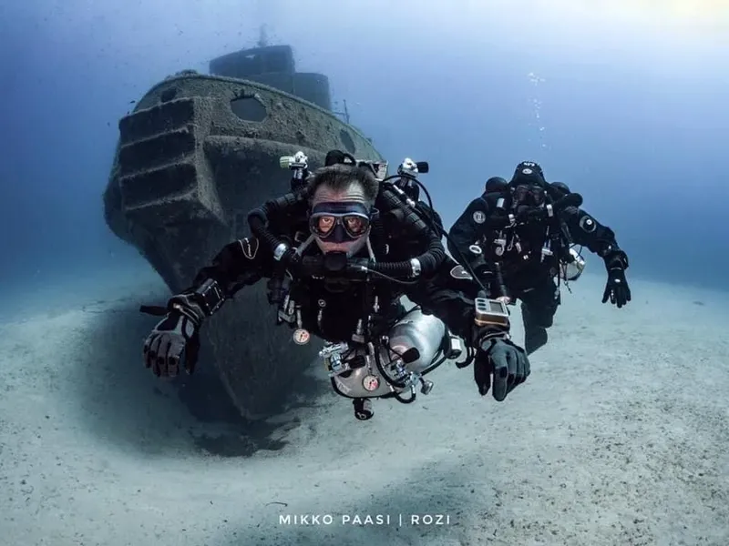 Trois plongeurs explorent l'épave d'un navire au fond marin