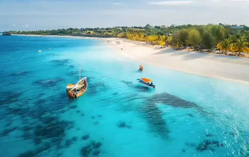 Vue aérienne d'une plage turquoise avec des bateaux de pêche et sable blanc