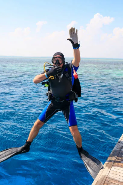 Plongeur équipé prêt à sauter dans une mer bleue et ensoleillée