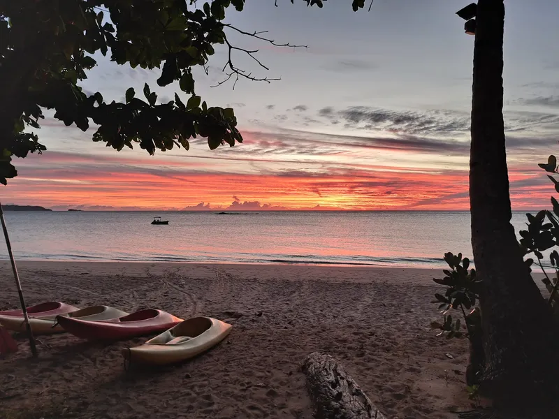 Coucher de soleil sur la mer avec un bateau au loin et kayaks