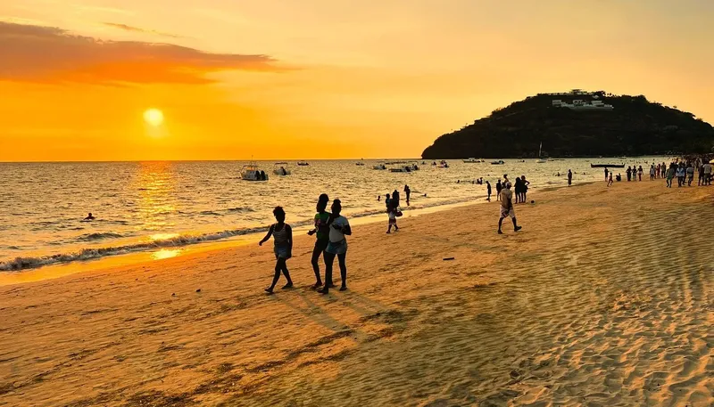 Plage ensoleillée avec des personnes se promenant au coucher du soleil