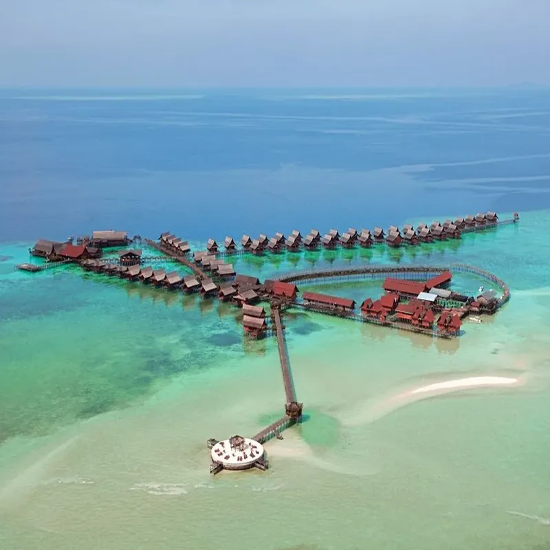 Vue aérienne d'un complexe hôtelier sur pilotis dans une eau turquoise