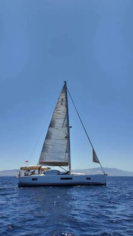 Catamaran à voile en mer, quelques personnes à bord, ciel bleu