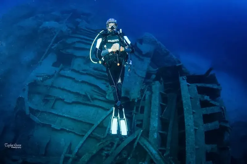 Plongeur explore un épave métallique sous l'eau en combinaison complète