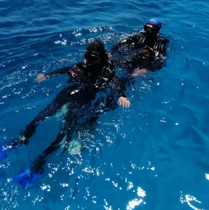 Deux plongeurs en combinaison nagent ensemble dans une eau bleue claire