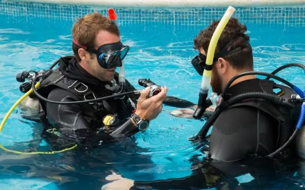 Deux plongeurs en formation manipulent l'équipement dans une piscine