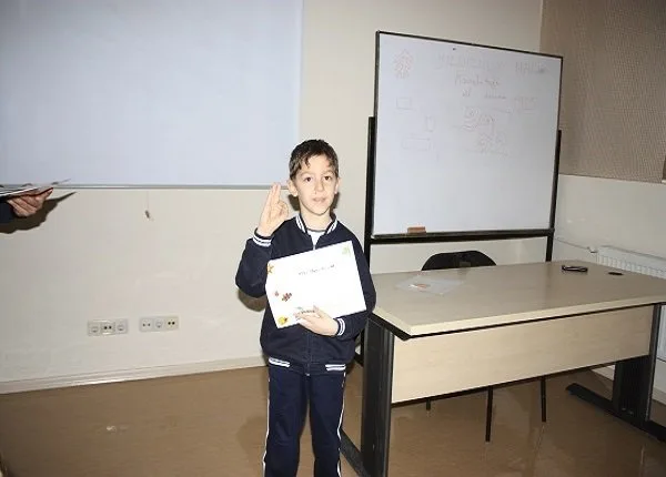 Un jeune garçon présente un document dans une salle de classe