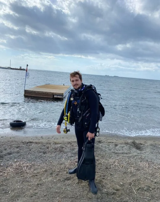 Plongeur en combinaison complète sur une plage avec son équipement