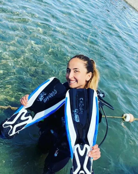 Plongeuse souriante sortant de l'eau avec ses palmes noires