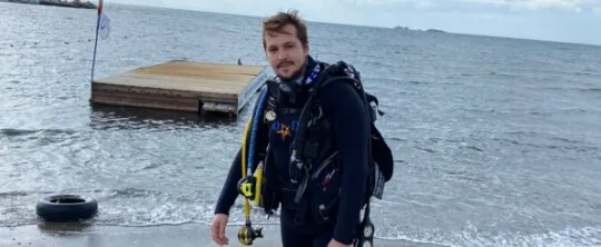 Plongeur équipé sur une plage avec un ponton en bois