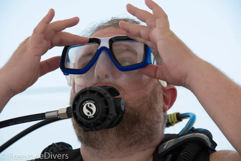 Plongeur ajustant son masque, équipement complet, regard vers le haut