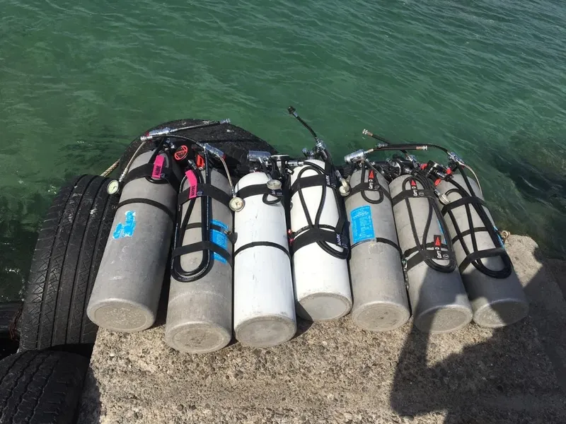 Bouteilles de plongée alignées sur un quai avec l'eau en arrière-plan