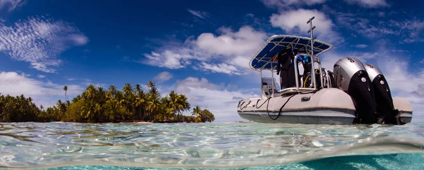 Demi-bateau de plongée sur l'eau turquoise, île tropicale en arrière-plan