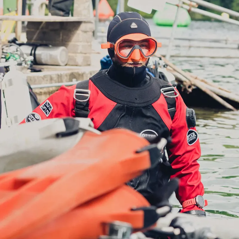 Plongeur en combinaison noire et masque orange sur un bateau