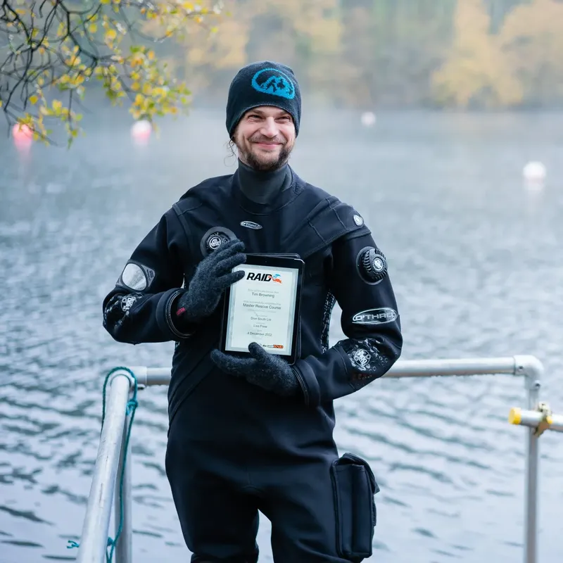 Plongeur souriant tenant un certificat de formation en eaux calmes