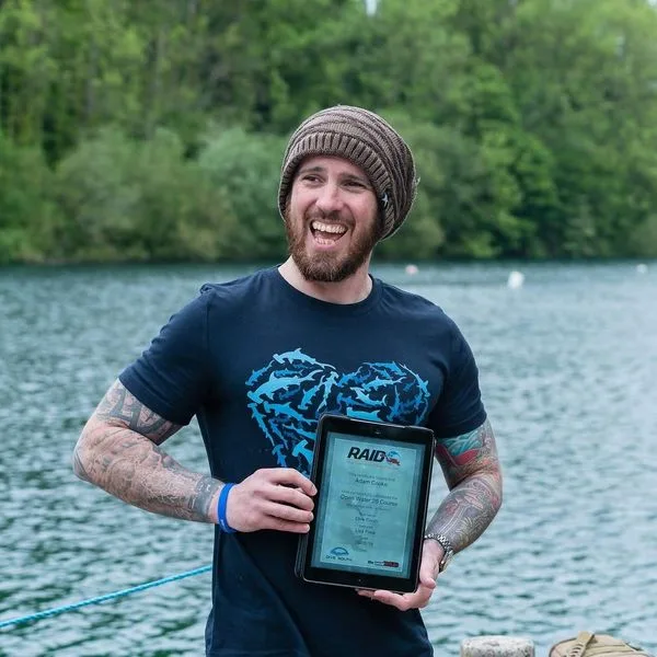 Un homme souriant tient un trophée de certification de plongée