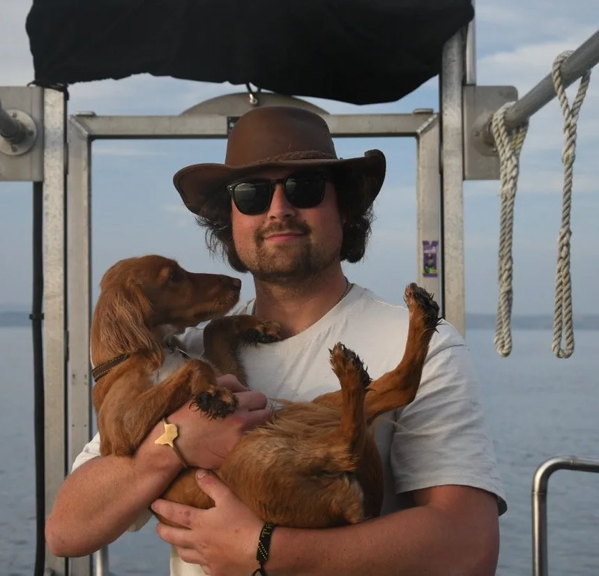 Un homme tient un chien marron sur un bateau en mer
