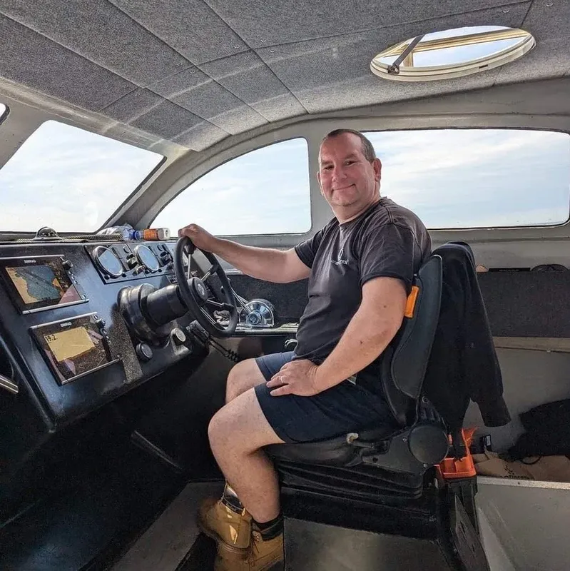 Homme souriant assis au volant d'un bateau de plongée