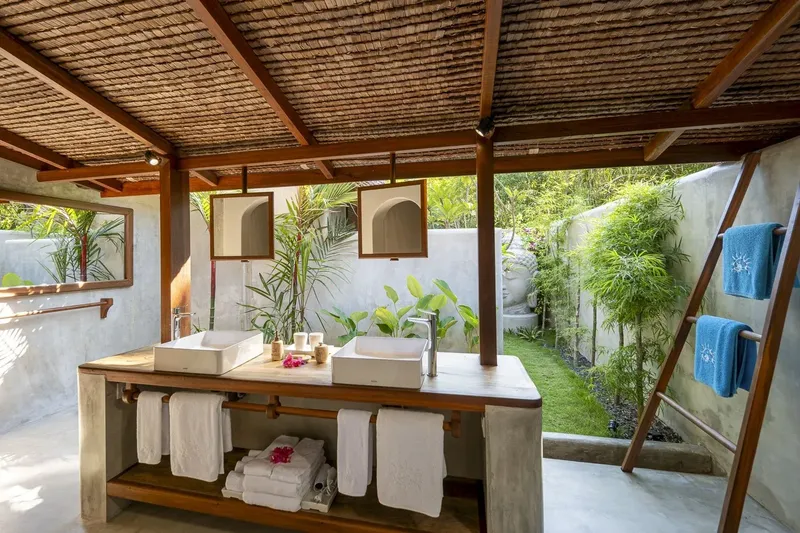 Salles de bain extérieures avec lavabos en pierre et végétation luxuriante