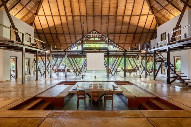 Grande salle ouverte avec structure en bois, table centrale et mezzanine