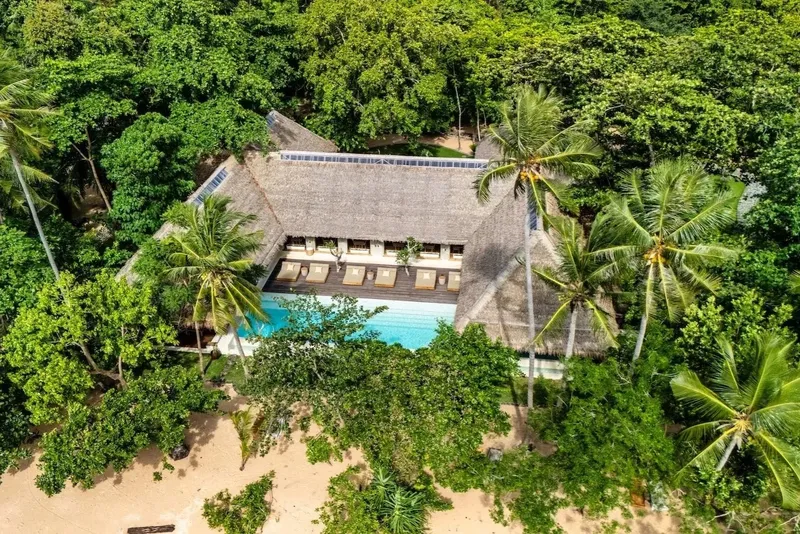 Vue aérienne d'un bâtiment avec piscine entouré de végétation tropicale