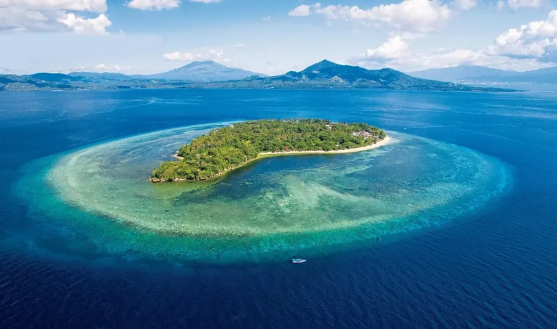 Île tropicale entourée d'un récif corallien et d'eaux turquoise