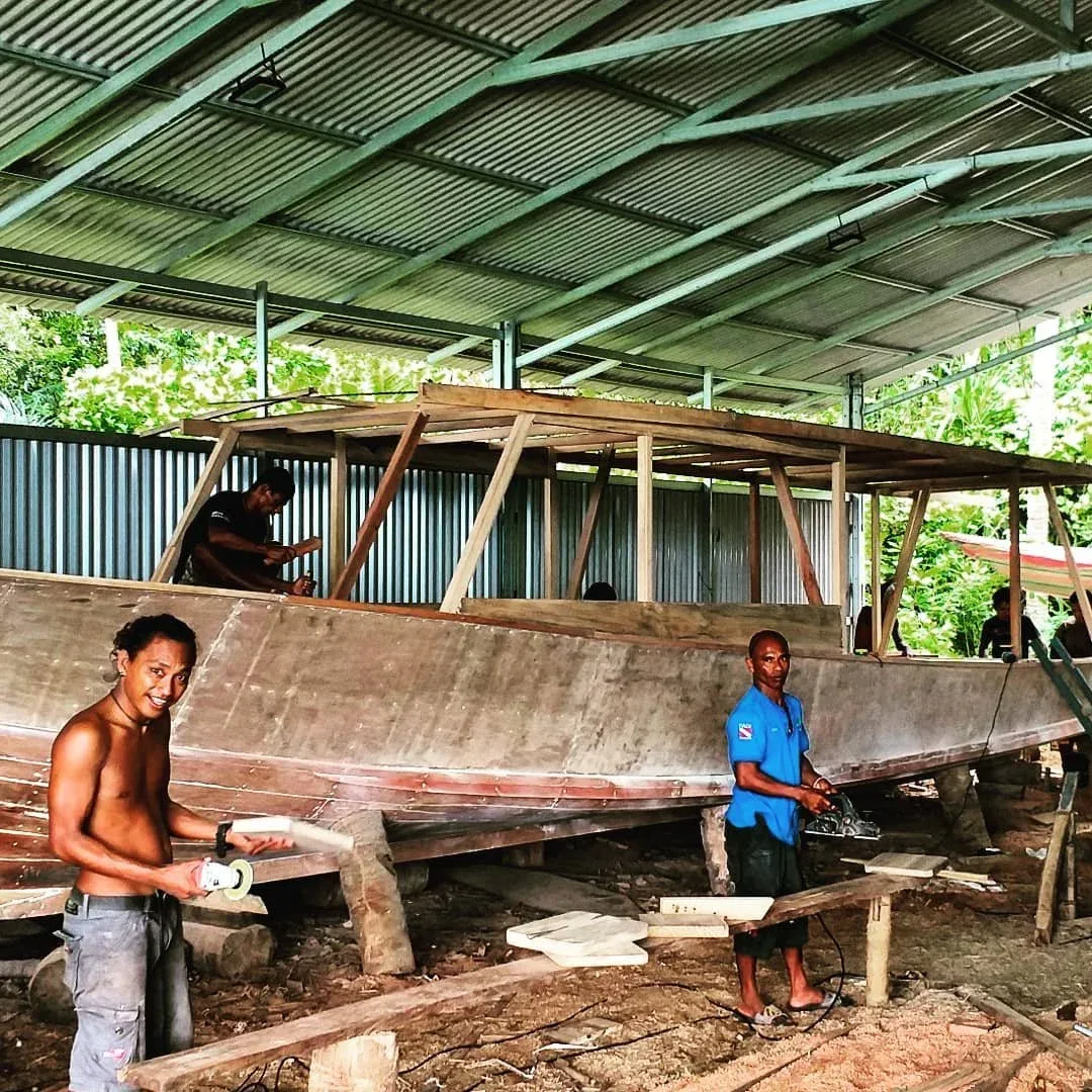 Construction d'un bateau en bois par des hommes souriants